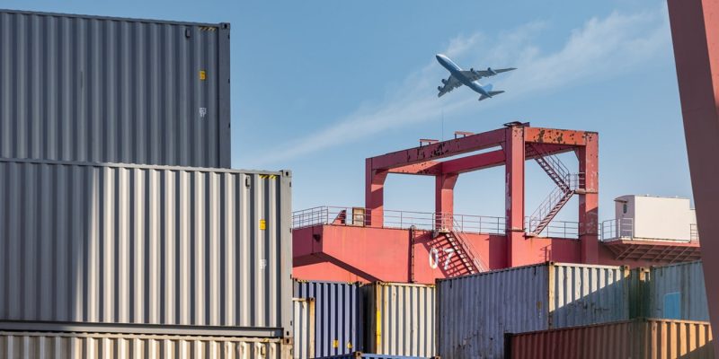 container-yard-closeup-with-airplane-in-sky-2023-11-27-04-50-06-utc.jpg